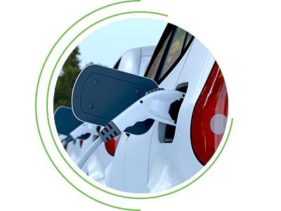 Close-up of an electric vehicle charging port with a plugged-in connector, framed within a circular graphic.