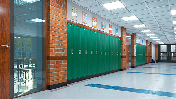 A school hallway with green lockers along a brick wall and classroom doors on one side.