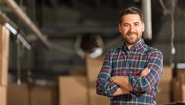 man wearing plaid shirt standing in a warehouse