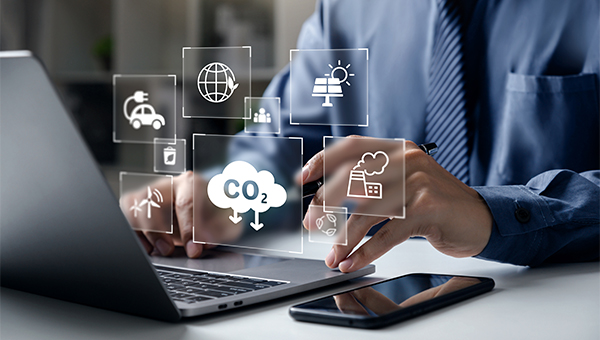 Person using a laptop with overlay icons representing sustainability concepts such as CO2 emissions, renewable energy, transportation, and industry.