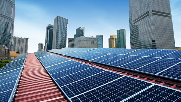 Solar panels installed on a rooftop with a city skyline of tall buildings in the background